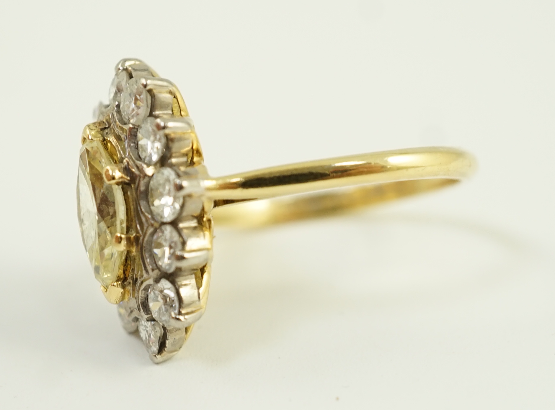 An 18ct gold and single stone fancy yellow diamond set marquise shaped cluster ring with round brilliant cut diamond set border